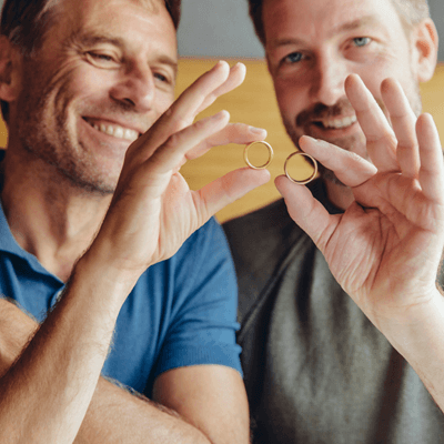 Happy gay couple holding up their wedding rings